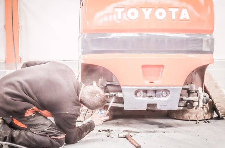 Técnico de Europa Elevación reparando una carretilla elevadora Toyota con herramientas especializadas en un taller profesional de carretillas elevadoras